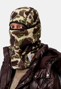 Pasamontañas de forro polar con un patrón de camuflaje que presenta tonos verdes, marrones y crema; banda negra alrededor de los ojos; textura cálida y suave.