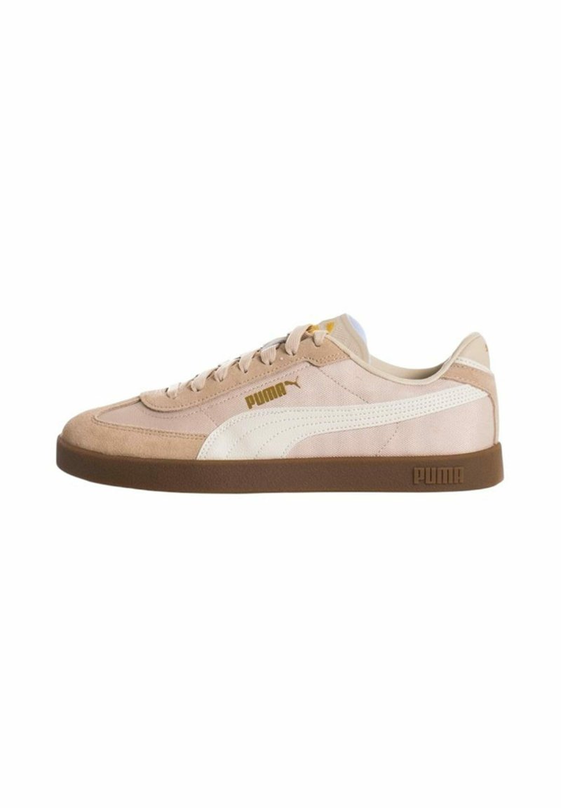 Zapatillas Puma con un upper de gamuza y tela en un tono beige claro, acentos blancos, diseño con cordones y una suela de goma marrón.