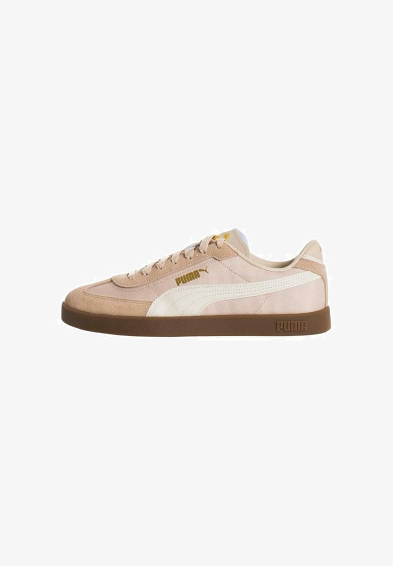 Zapatillas Puma con un upper de gamuza y tela en un tono beige claro, acentos blancos, diseño con cordones y una suela de goma marrón.