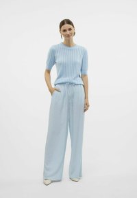 Maglione azzurro chiaro lavorato a maglia con maniche corte, caratterizzato da un motivo a trama e vita aderente, abbinato a pantaloni larghi coordinati azzurro chiaro.