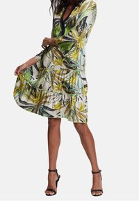 Robe fleurie en tissu léger, ornée de motifs de feuilles vertes et jaunes, décolleté en V, manches trois-quarts et ourlet volanté.