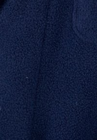 Dunkelblaues Fleece-Gewebe, weiche Textur mit einem leichten Glanz. Die Oberfläche hat ein einheitliches, plüschiges Aussehen ohne sichtbare Muster oder Hardware.