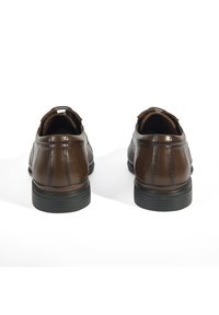 Bruine leren schoenen met een gladde afwerking, voorzien van een laag profiel en textuuraccenten. Rubber zolen bieden grip en stabiliteit.