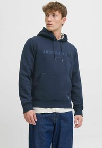 Sudadera azul marino con bolsillo tipo canguro, con un estampado de logo tonal. Fabricada en un tejido suave con un corte relajado y capucha ajustable con cordón.