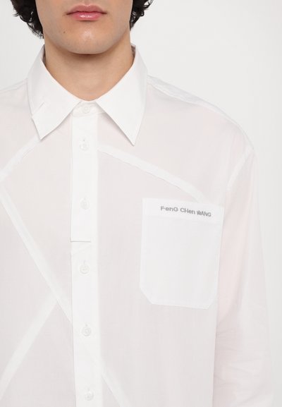 Camisa blanca de botones, hecha de una tela ligera, que presenta un patrón geométrico, cuello tipo punta y un bolsillo en el pecho izquierdo con un detalle de logo.