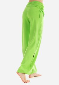 Helle grüne, weit geschnittene Hose aus glattem Stoff. Verfügt über einen gerafften Taillenbund mit verstellbarem Kordelzug und Seitenschlitzen.