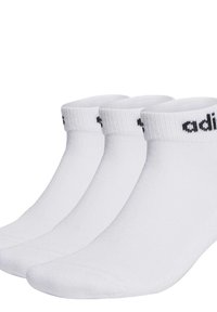 Chaussettes blanches en coton, mi-mollet avec des bords côtelés, arborant le logo noir "adidas" sur chaque bord. Présentées dans un ensemble de trois paires.