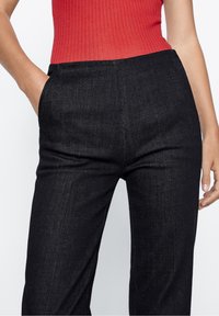 Hoge zwarte denim broek met een gladde textuur, zijzakken en een rechte pijpontwerp, gecombineerd met een aansluitende ribben rode top.