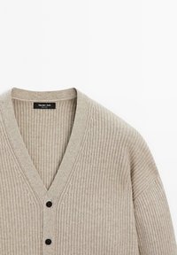 Beige ribgebreide cardigan met V-hals, twee zwarte knopen en het merklabel "Massimo Dutti" aan de binnenkant van de kraag.