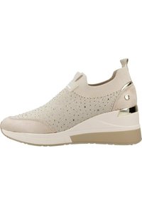 Zapatillas slip-on beige con parte superior de punto, que presentan acentos metálicos, una punta texturizada y una suela de cuña con un sutil diseño gris.