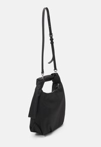 Borsa a mano in tessuto nero con manico annodato, tracolla regolabile e ferrature in argento. Presenta un design morbido e morbido e un'estetica minimalista.