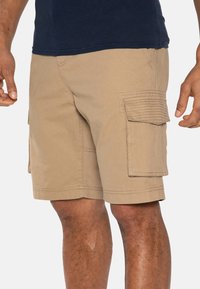 Shorts cargo beiges en tissu robuste, avec de multiples poches latérales et des détails de couture subtils. Conçus pour la praticité et le confort.