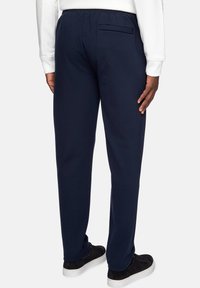 Navy blue sweatpants with elastic waistband and a single back pocket, made of soft fabric, paired with black sneakers.