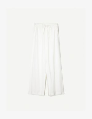 Witte wijde broek met een trekkoord in de taille, weergegeven tegen een effen achtergrond, wat de ontspannen stijl en de textuur van de stof benadrukt.