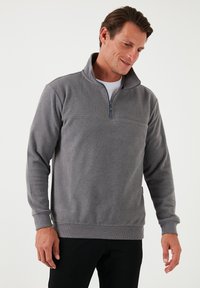 Pullover in pile grigio con colletto alto, chiusura a mezza zip, polsini e vita a costine, caratterizzato da una texture liscia e un colore uniforme.