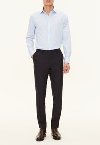Camicia blu chiara a righe, dallo stile slim fit, abbinata a pantaloni navy. Scarpe eleganti in pelle marrone completano l'outfit.