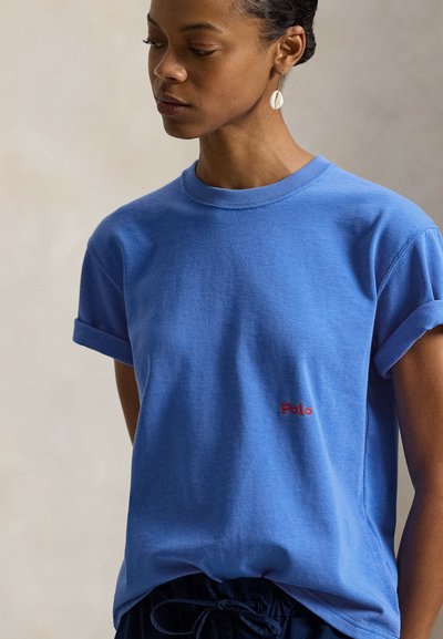 Μπλε βαμβακερό μπλουζάκι με γυρισμένα κοντά μανίκια, με μικρό κόκκινο λογότυπο "Polo" στην αριστερή πλευρά του στήθους. Μαλακή υφή και άνετη εφαρμογή.