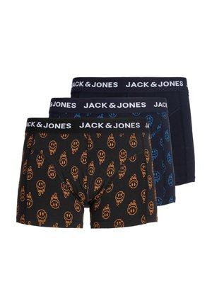 Jeune homme torse nu aux cheveux blonds courts portant un boxer noir avec des motifs de smileys orange et une ceinture de marque Jack & Jones.