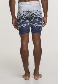 Pantaloni shorts fitting da uomo con un motivo tribale geometrico in tonalità di blu e grigio. Realizzati in materiale elasticizzato con una vita elastica bianca.