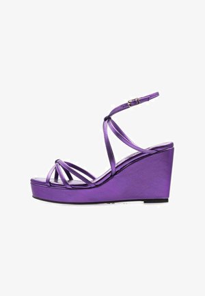 Sandalias de cuña moradas con finas tiras entrelazadas, un acabado metálico suave y una base de plataforma para mayor altura. Cierre con hebilla en el tobillo.
