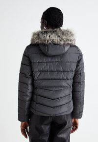 Grijze pufferjack met een capuchon met kunstbontafwerking, horizontaal gewatteerd ontwerp en ribgebreide manchetten. Zichtbare naden aan de achterkant.