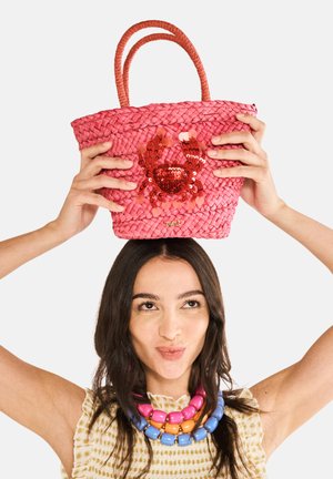 Rosa geflochtene Einkaufstasche mit zwei Griffen, die ein Pailletten-Krebsdesign aufweist. Die Tasche hat eine strukturierte Oberfläche und ein goldenes Logo-Detail am Boden.