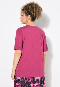 Fuchsia t-shirt met korte mouwen, ronde halslijn en opgerolde mouwen. Stof lijkt zacht met een lichte heather structuur.