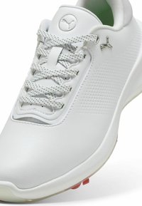 Vit syntetisk sneaker med texturerade paneler, grå och vita snören, med en logotypdetalj på tungan och en genomskinlig sula.