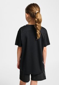 T-shirt sportif noir à manches courtes et coupe décontractée, associé à un short noir. Le tissu semble lisse et léger sans motifs visibles.