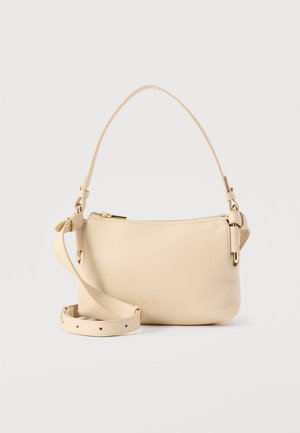 Beige skuldertaske i læder med guldlukning, justerbar længere rem og fast kort håndtag på ensfarvet baggrund.