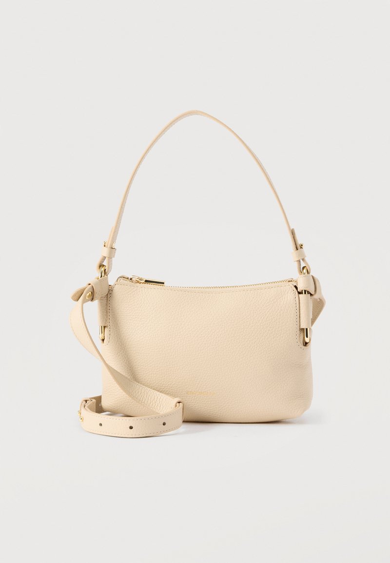 Μπεζ δερμάτινη τσάντα ώμου με χρυστό φερμουάρ, ρυθμιζόμενο μακρύτερο λουρί και σταθερό κοντό χερούλι σε απλό φόντο.