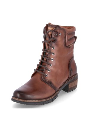 Bottine en cuir marron avec un bout arrondi, des lacets contrastants, des œillets en métal et un talon carré texturé. Présente des accents de couture.