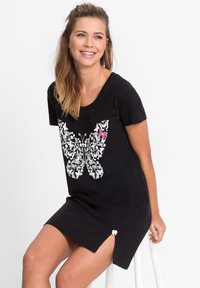 Abito T-shirt in cotone nero con una grande grafica di una farfalla bianca e rosa, maniche corte e spacchi laterali con dettagli bianchi.