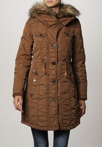 Brun pufferjakke med faux fur hætte, lynlås- og knaplukning, fire frontlommer og kviltet design. Struktureret stof med en let følelse.