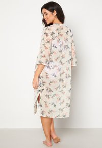 Květinový kimono stylový župan v světlé béžové, průhledná tkanina s fialovými a oranžovými květinovými vzory, s širokými rukávy a bočními rozparky.