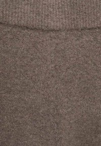Brun filttyg med en mjuk, strukturerad yta. Har en ribbadsstrickning upptill och ett slätt, enhetligt utseende genom hela tyget.
