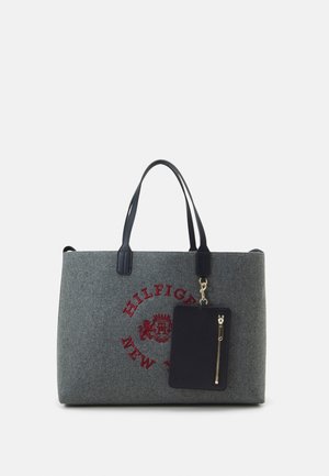 Sac cabas gris avec poignées noires, logo rouge "Hilfiger New York" et pochette noire zippée attachée.