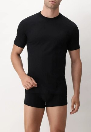 T-shirt nera a maniche corte realizzata in un tessuto liscio, con scollatura rotonda e taglio classico, abbinata a pantaloni corti neri aderenti.