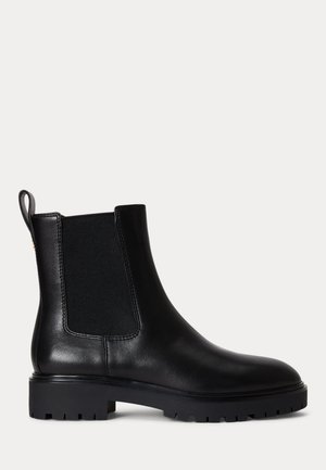Bottine noire en cuir avec panneaux latéraux élastiques, languette à l'arrière, et semelle extérieure épaisse en caoutchouc à crampons avec petit talon.