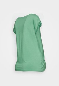 Camisa verde de manga curta, feita de tecido suave, com um decote arredondado e um ajuste descontraído. Textura suave com as bainhas das mangas dobradas.