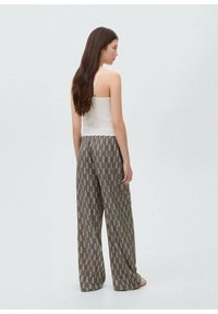 White ribbed crop top paired with loose, patterned brown pants featuring a leaf design. The fabric appears soft and breathable.