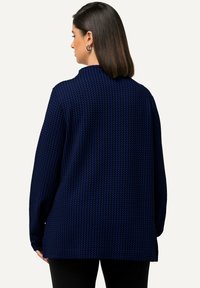 Maglione lavorato a maglia blu navy con un motivo testurizzato, vestibilità comoda e colletto. Presenta spalle scese e maniche lunghe.