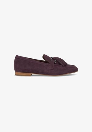 Dunkelviolette Wildlederschuhe mit flacher Sohle, ausgestattet mit einem dekorativen Quasten- und Metallakzent. Glatte Textur mit minimalistischem Design.
