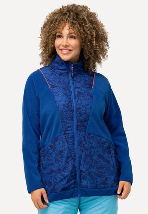 Veste en polaire bleue avec un motif texturé. Dotée d'un col montant, d'une fermeture éclair sur le devant et d'accents orange contrastants. Deux poches latérales.