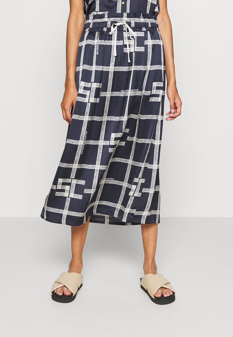 Jupe midi marine avec un motif à carreaux blancs et des accents de logo. Elle dispose d'une taille élastique avec cordon de serrage, d'un tissu léger et d'une coupe fluide.