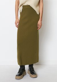 Olijfgroene, geribbelde maxi-rok met een aansluitende tailleband, gecombineerd met zwarte veterschoenen met een chunky profiel en een dikke beige zool.