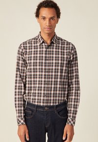 Geruite button-up shirt in een katoenmix; kleuren zijn marineblauw, wit en roest. Lange mouwen en klassieke kraag, gecombineerd met donkere spijkerbroek.