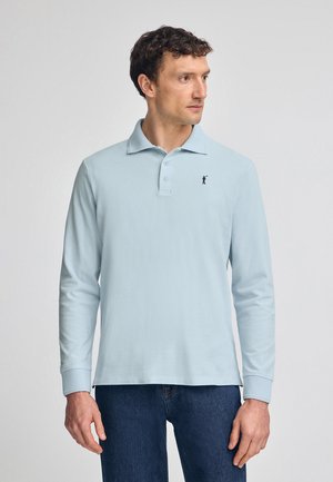 Helles blaues Langarm-Polohemd mit Kragen, drei Knöpfen und einem kleinen schwarzen Logo auf der linken Brust. Glatte Stoffstruktur.