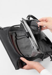 Borsa in pelle nera con chiusura a zip, dotata di un interno foderato grigio, scomparti per l'organizzazione e una maniglia robusta.