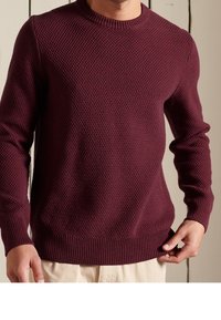 Pull en maille bordeaux avec un motif texturé, encolure ronde, et poignets et ourlet côtelés. Coupe ajustée, fabriqué en matériau doux.